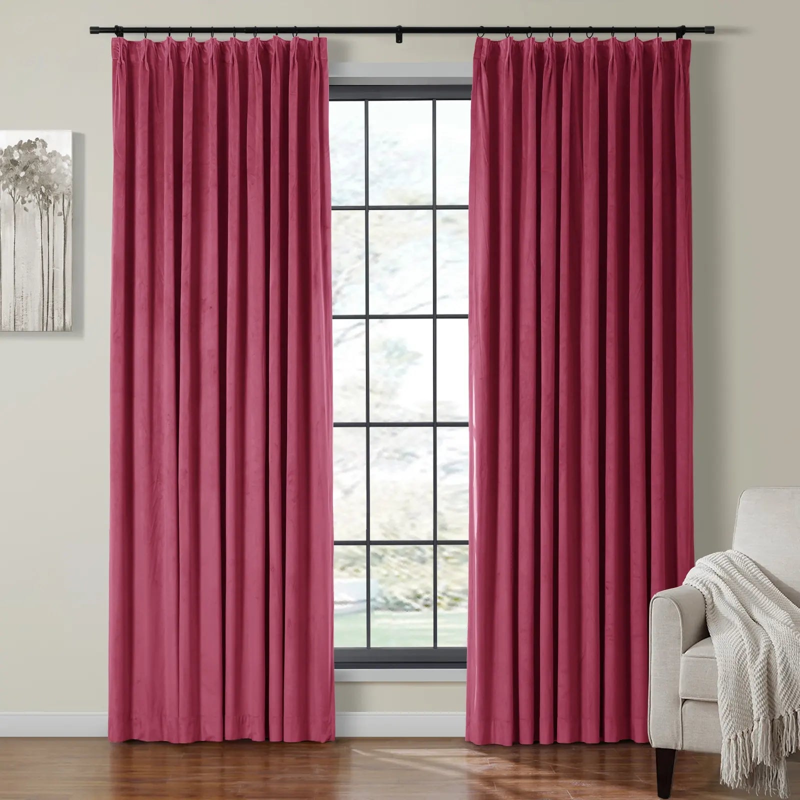 Photograph of a modern living room featuring a large grid-pane window flanked by rich berry red velvet pleated curtains on a black rod, complemented by a minimalist gray tree painting and a cream armchair with a textured throw blanket