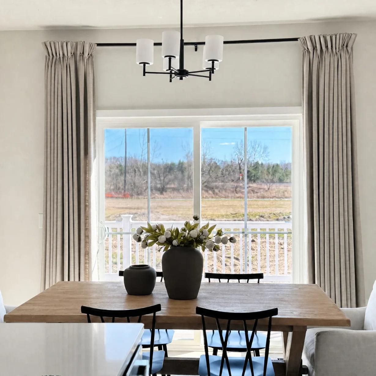 Burlywood Birch Liz Linen Pleated Curtains framing sliding patio doors behind a dark wood dining table