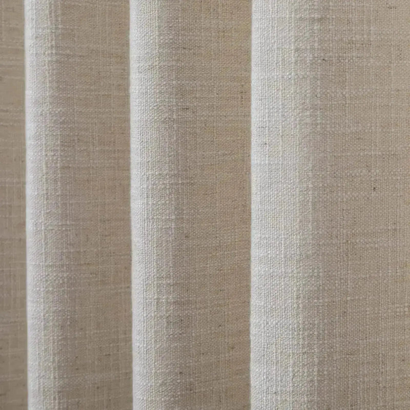 A close-up photograph of natural light beige textured fabric showing visible vertical folds and a coarse weave
