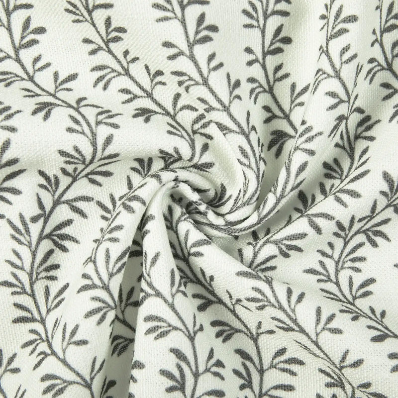 Textile featuring a repeating dark grey botanical leaf pattern on a textured white fabric with a prominent central swirl