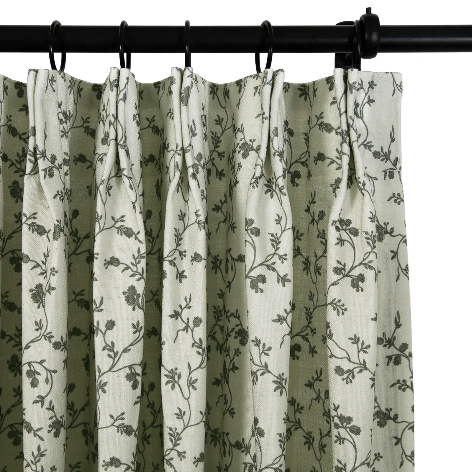 Fabric pleated curtain in light beige featuring a dark grey floral vine pattern hanging from a black curtain rod with black rings