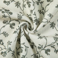 Off-white textured fabric with a delicate dark grey floral vine pattern featuring a prominent central swirl