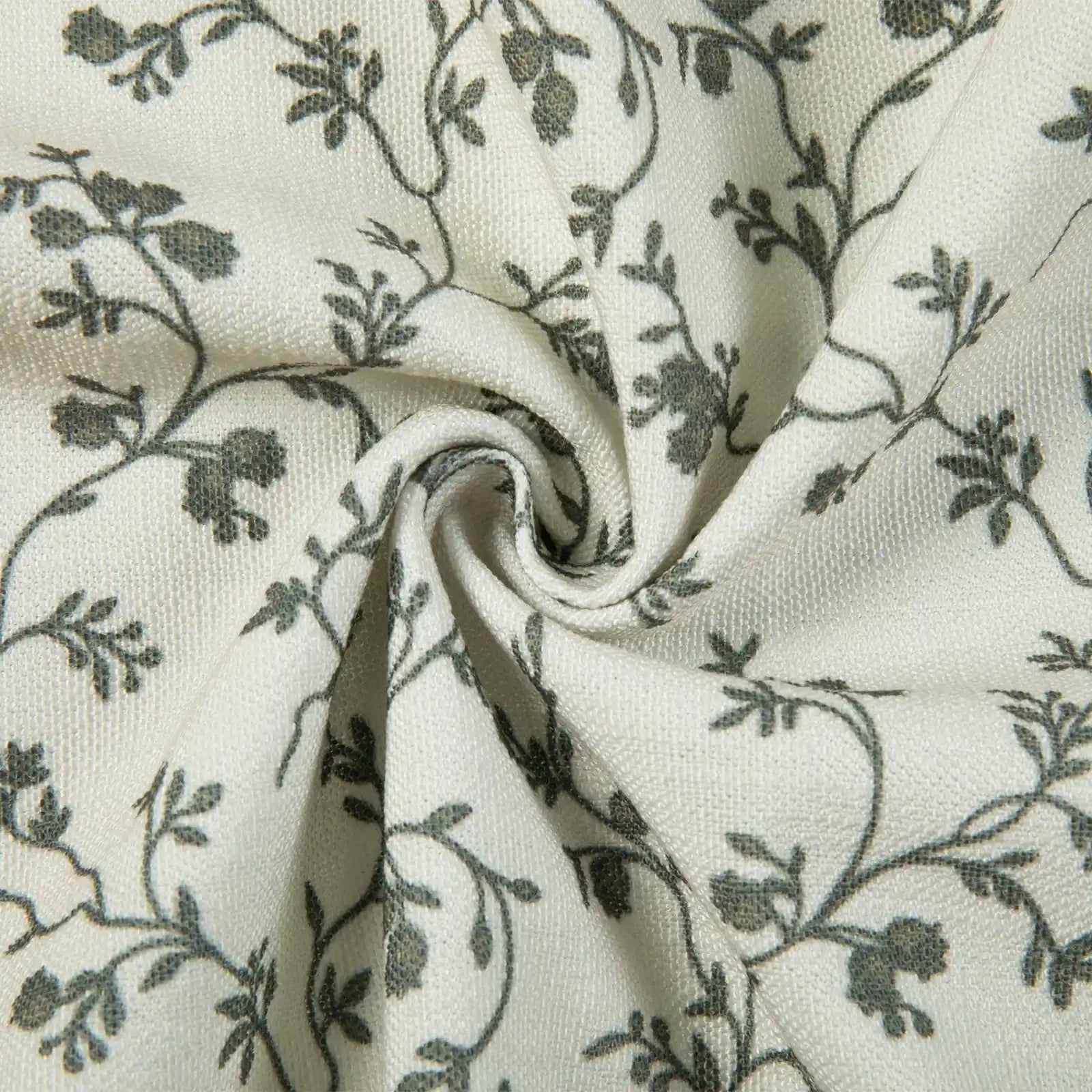 Off-white textured fabric with a delicate dark grey floral vine pattern featuring a prominent central swirl