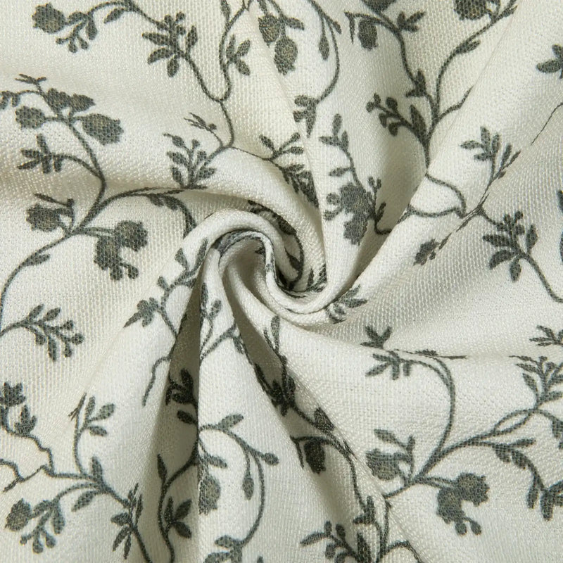 Off-white textured fabric with a delicate dark grey floral vine pattern featuring a prominent central swirl