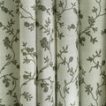 Textile patterned curtains featuring an off-white background with delicate gray-green floral vine motifs and a visible woven texture