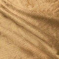 Textured warm golden brown fabric softly draped with crinkled folds highlighting its subtle shimmer and woven thread details