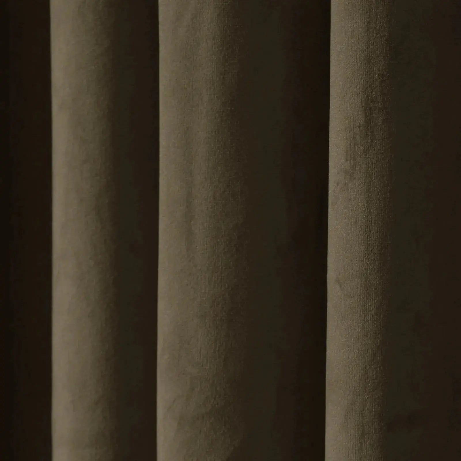 A close-up of a dark brown textured curtain featuring deep vertical folds, a velvety fabric surface, and muted olive-green and dark brown tones highlighted by soft light