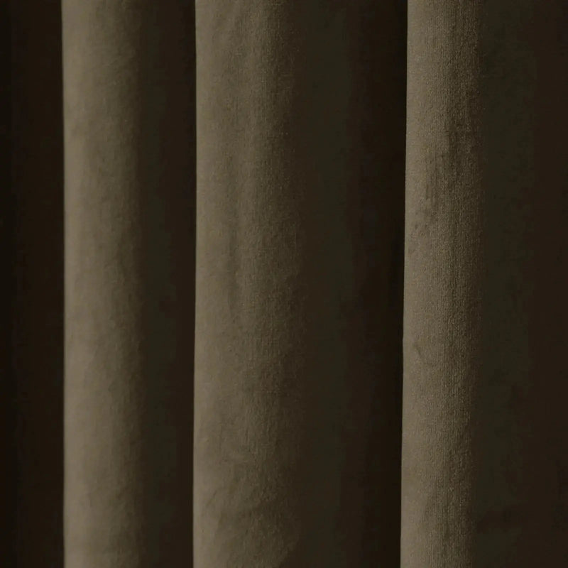 A close-up of a dark brown textured curtain featuring deep vertical folds, a velvety fabric surface, and muted olive-green and dark brown tones highlighted by soft light