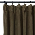 Close-up of a dark olive green heavy fabric curtain with a gathered top edge suspended by black rings from a black metal rod showing prominent vertical folds