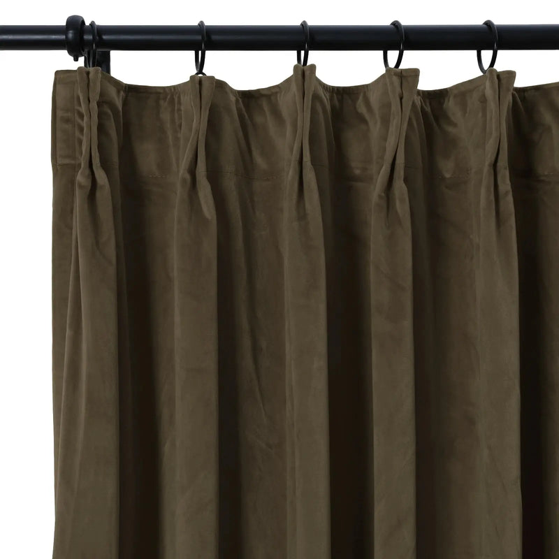 Close-up of a dark olive green heavy fabric curtain with a gathered top edge suspended by black rings from a black metal rod showing prominent vertical folds