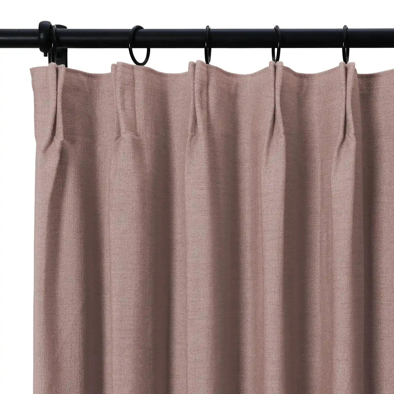 Photograph of a mauve woven fabric curtain panel with pinch pleat heading hanging from a black metal rod and rings