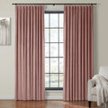 Dusty rose pink velvet pleated curtains framing a black-gridded window in a contemporary room featuring a light grey armchair with a cream throw and abstract tree wall art
