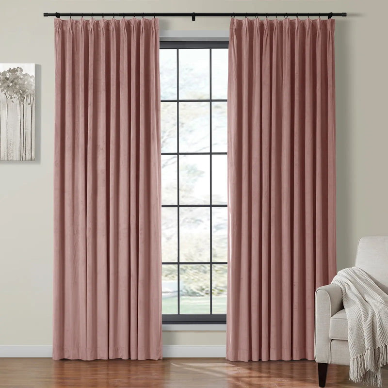 Dusty rose pink velvet pleated curtains framing a black-gridded window in a contemporary room featuring a light grey armchair with a cream throw and abstract tree wall art