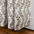 Textile print of a white textured curtain with a repeating brown stylized leaf pattern draped over a rich dark wooden floor next to a white baseboard