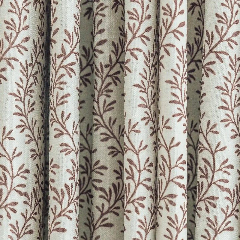 Woven fabric curtain with a light cream base and vertical pleats adorned with a repeating reddish-brown botanical leaf design