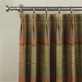 A close-up of a tweed plaid curtain in olive green rust and brown with subtle blue and pink lines featuring a pencil pleat heading and brushed metal rod and rings