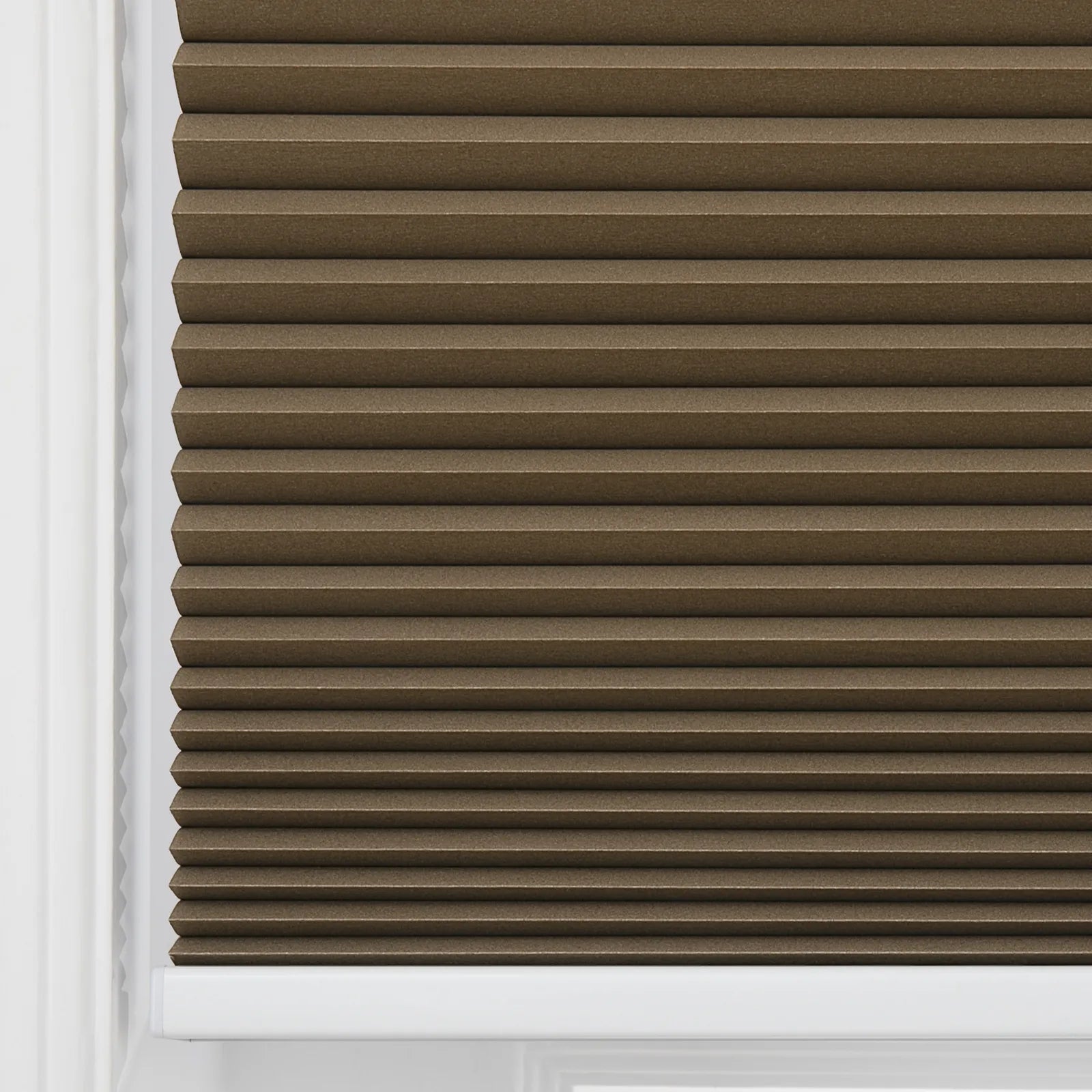 A brown textured pleated cellular window Blind with horizontal pleats installed within a clean white window frame