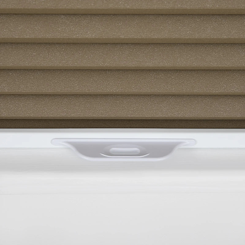 Close-up of a brown textured pleated cellular window Blind with a white bottom rail and an integrated white pull handle resting on a white window sill