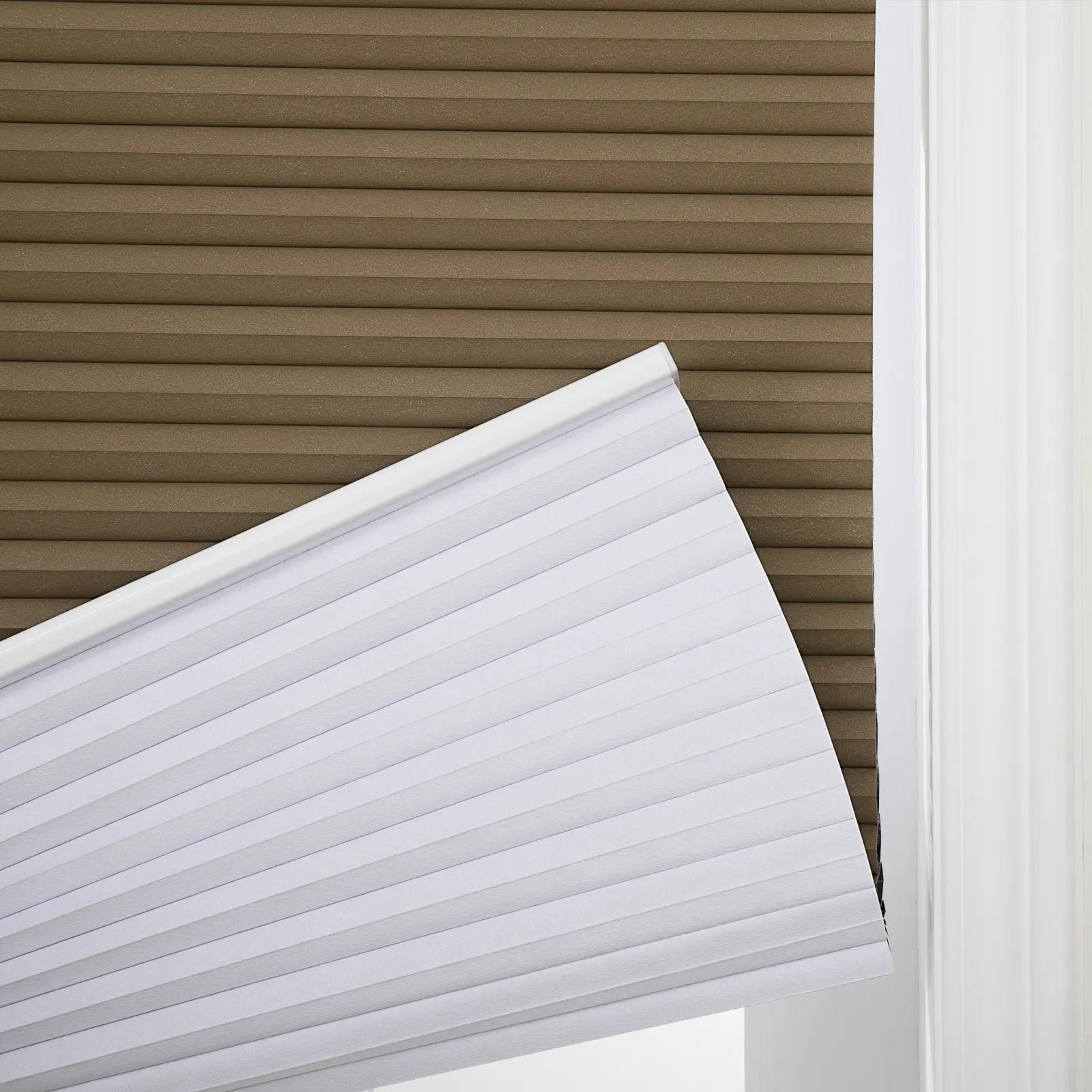 A close-up of white cellular window Blinds partially open, revealing brown cellular Blinds and a white window frame
