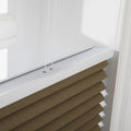Photograph of a brown textured cellular window Blind with a white headrail and visible thin white control cords installed on a white window frame