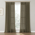 Dark olive-brown textured window curtains with a repeating white floral block print pattern, suspended from a brass rod, illuminating a room with light hardwood floors and a framed palm tree art print on the left wall