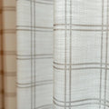Close-up of light beige textured fabric curtain featuring a subtle brown grid pattern and soft vertical folds