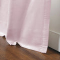 Photograph of a soft pink velvet curtain pooling slightly on a rich brown wooden floor against a white baseboard