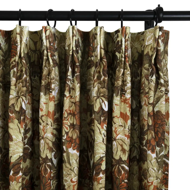 Textile curtain displaying a dense, vintage-style floral motif in shades of olive green, brown, rust orange, and cream, neatly pleated and suspended from a black curtain rod with rings
