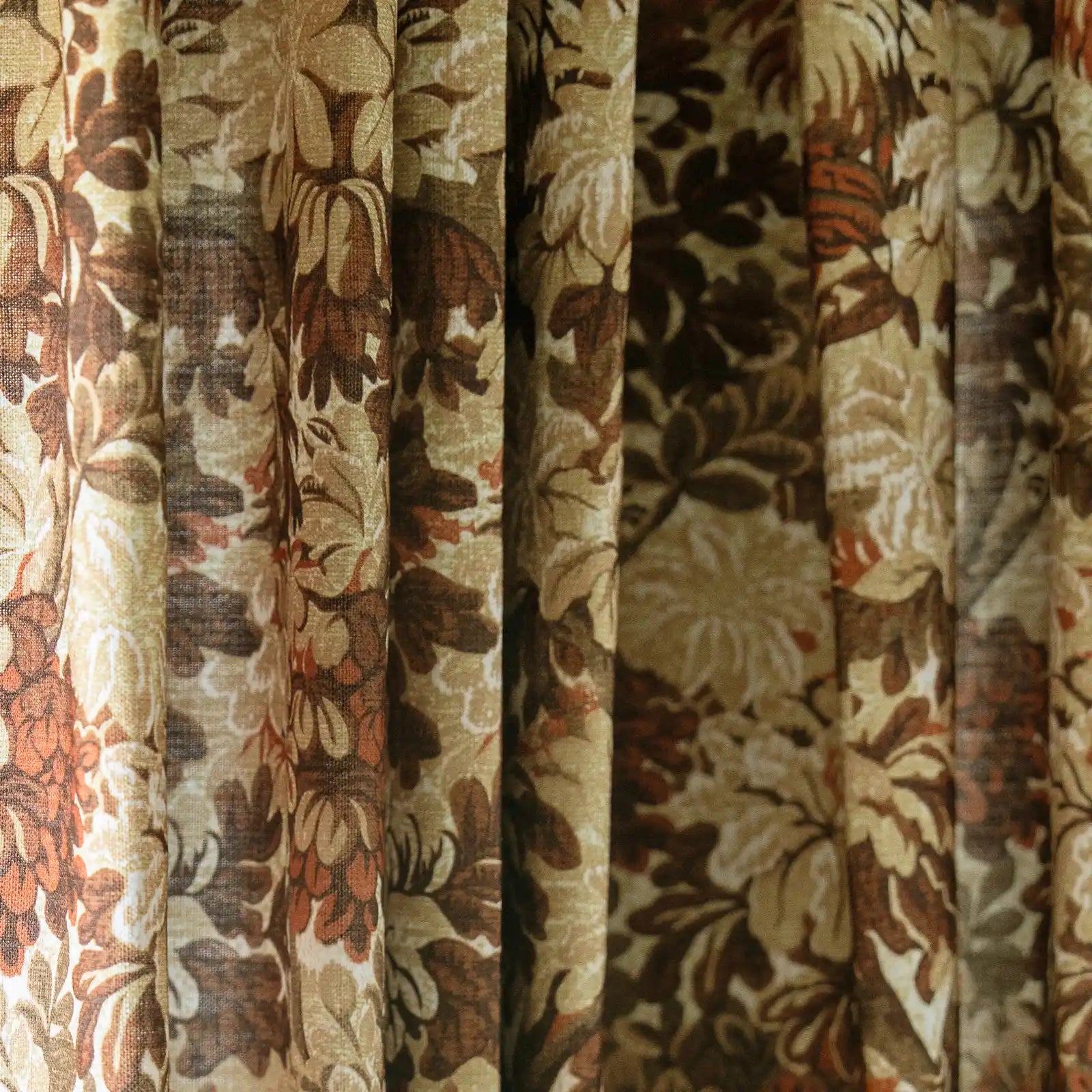 Digital photograph of heavily draped curtains featuring an intricate floral pattern in shades of brown, cream, beige, and subtle rust orange