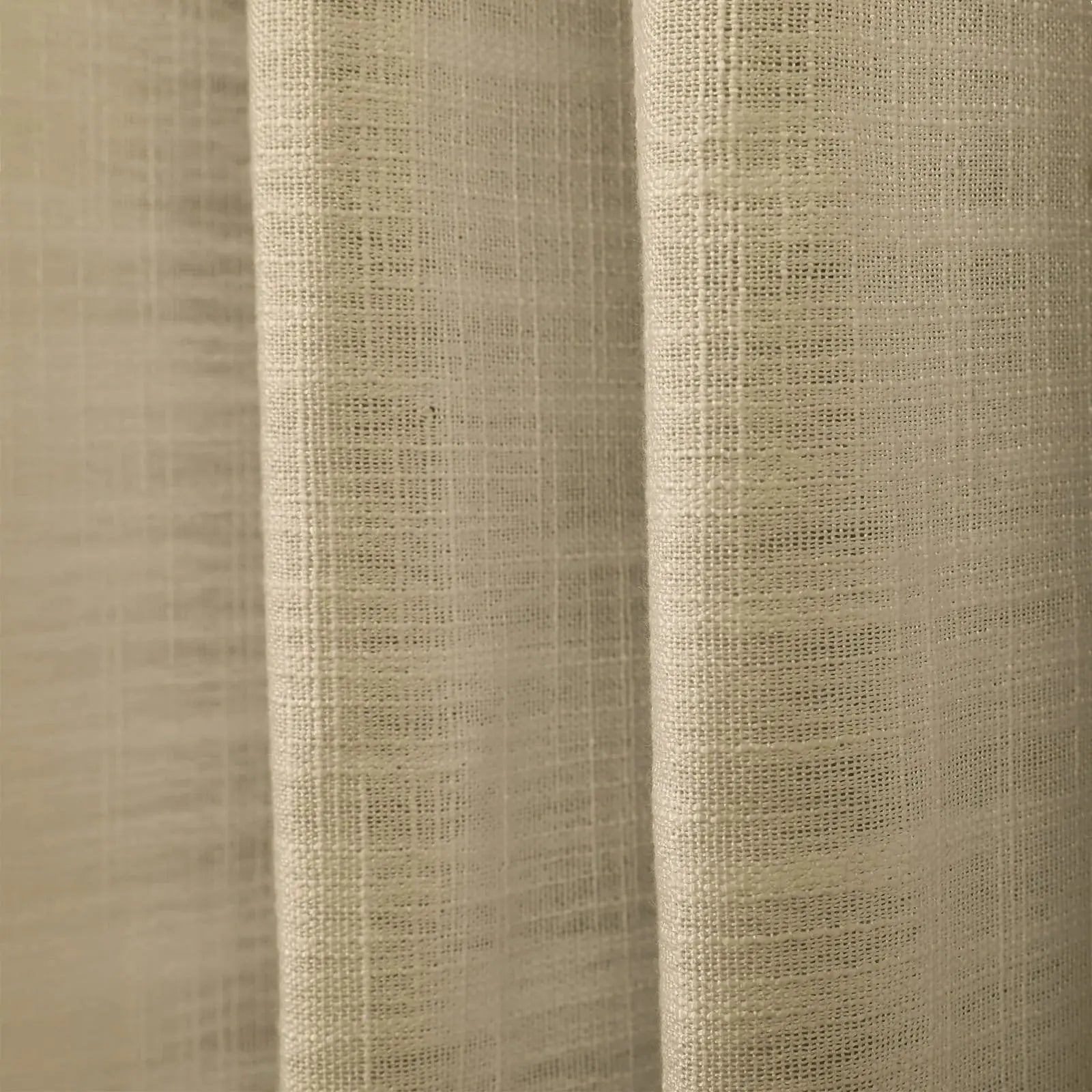 Close-up of neutral beige textured fabric revealing intricate woven details and gentle vertical folds under soft illumination