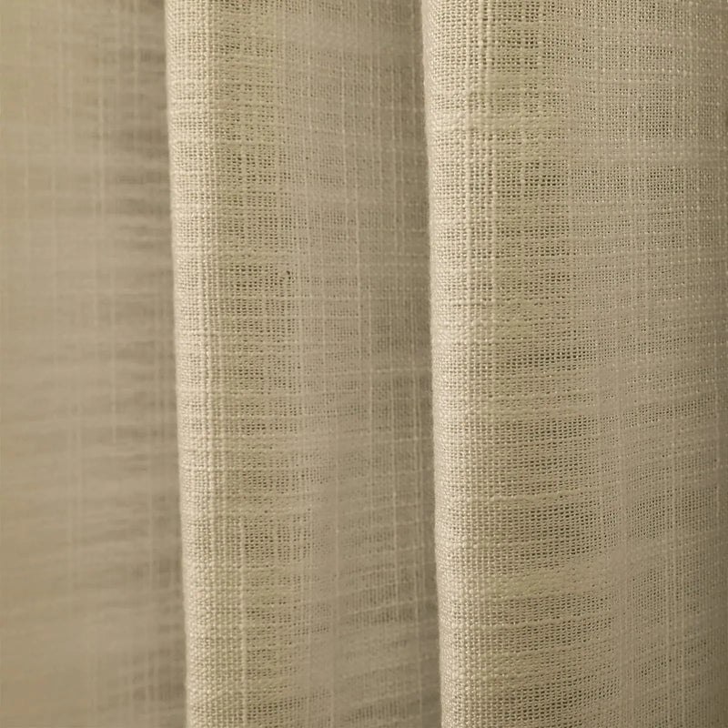 Close-up of neutral beige textured fabric revealing intricate woven details and gentle vertical folds under soft illumination