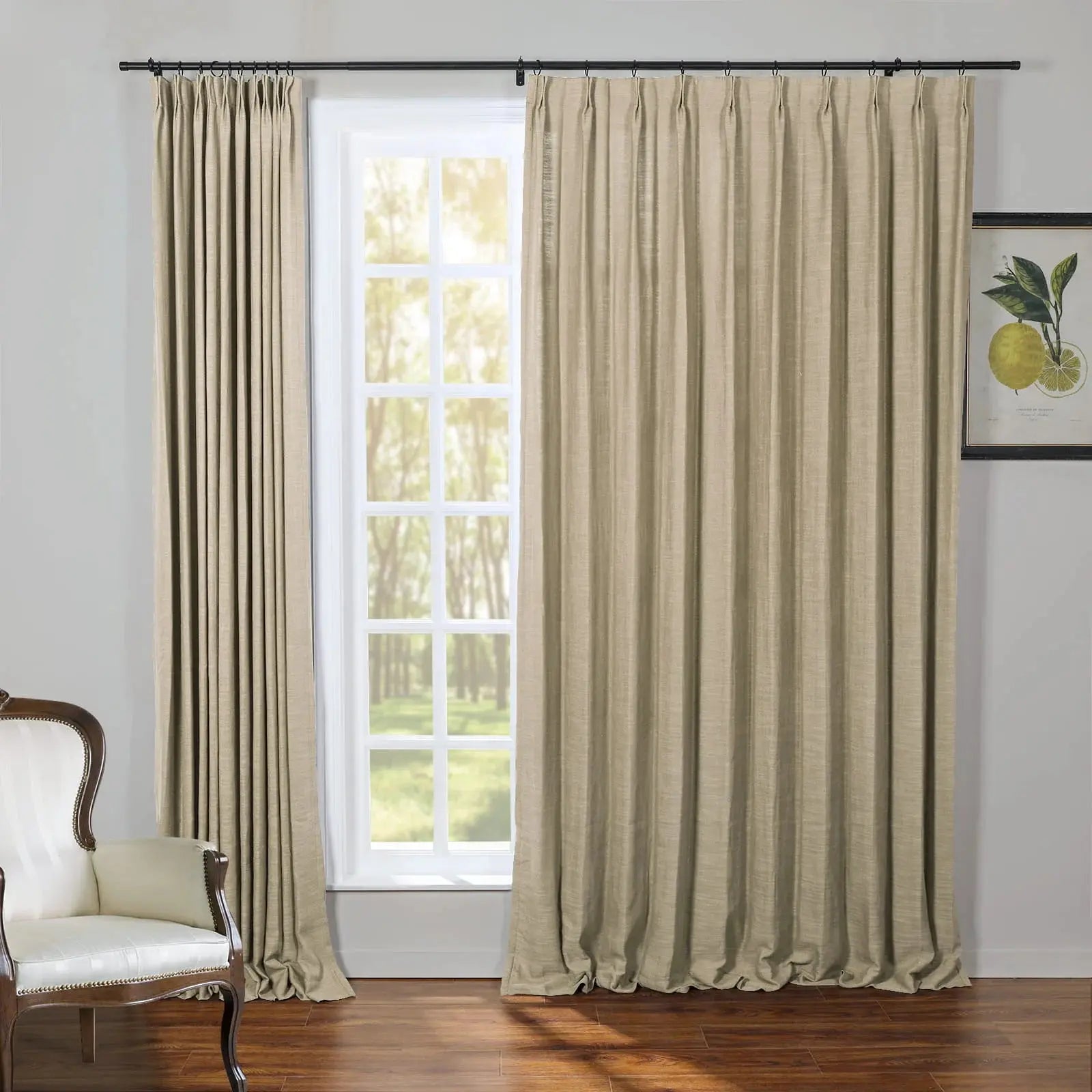 Beige textured draperies on a black rod frame a multi-pane window revealing a lush green outdoor view, complemented by an elegant white upholstered armchair with dark wood trim and a vibrant yellow lemon botanical print