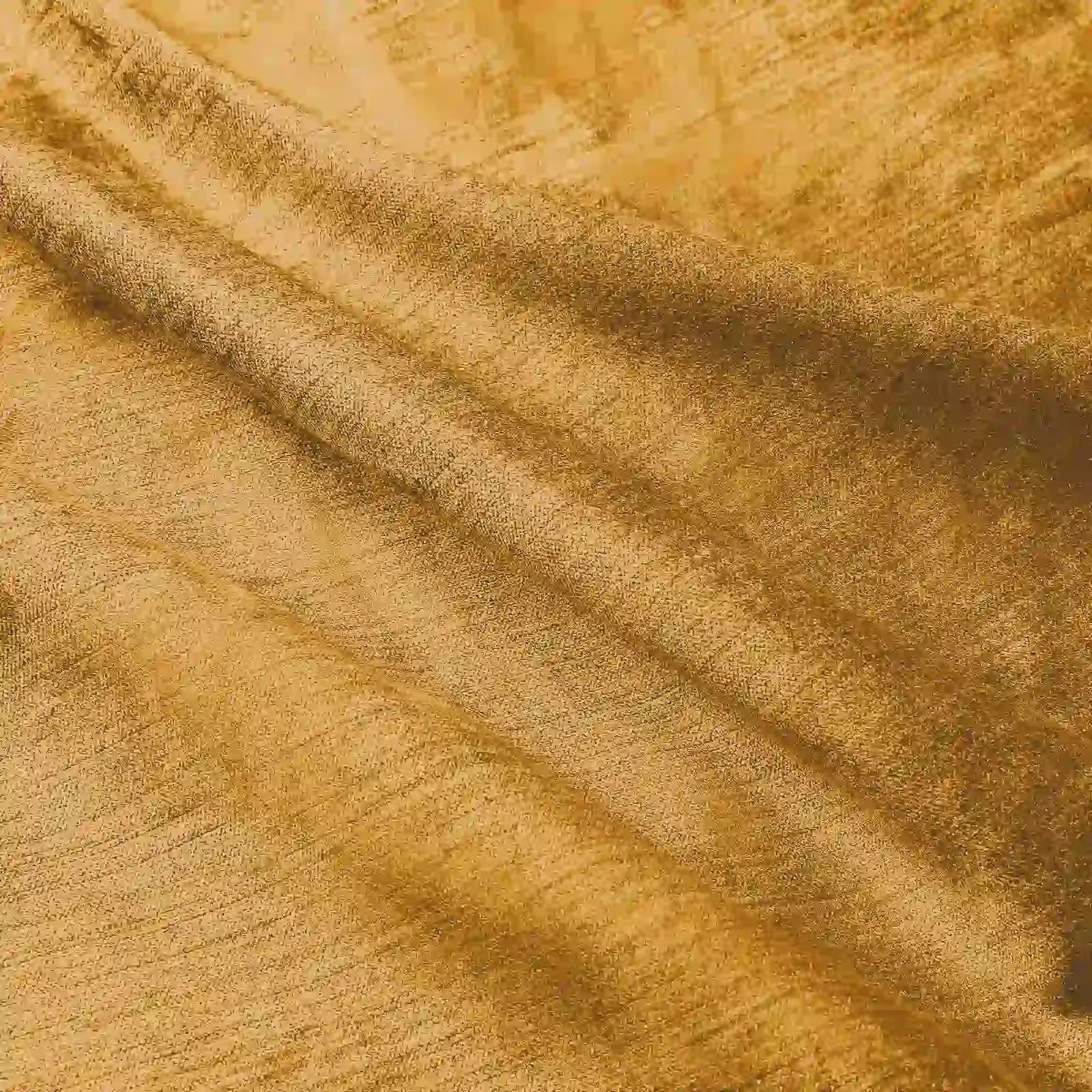 Photograph of golden-yellow textured fabric showing intricate subtle shimmer and soft diagonal folds creating gentle highlights and shadows