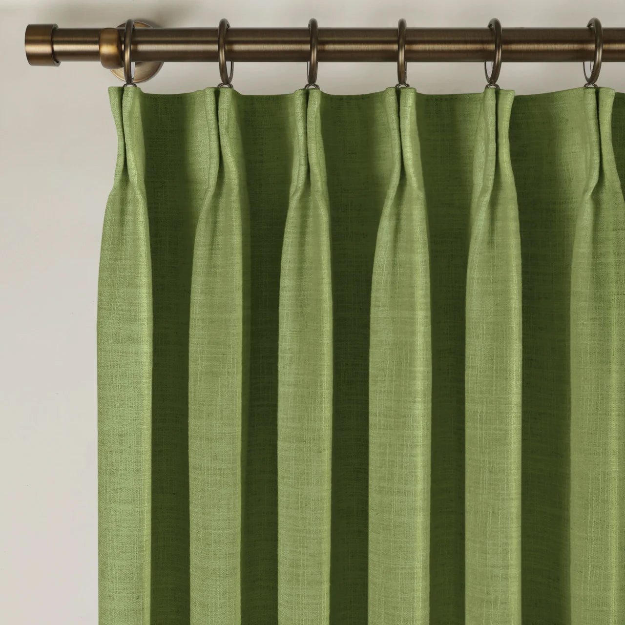 Green Liz linen curtains viewed at an angle in a softly styled room with natural daylight