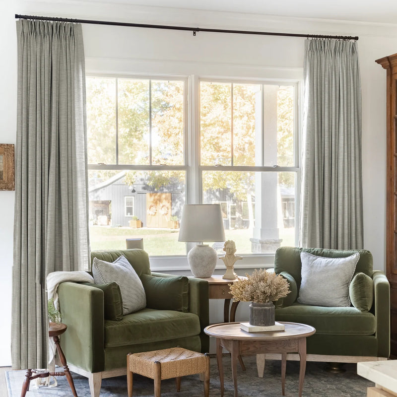 Grey Liz Linen Pleated Curtains framing a green sofa beneath a wide sunlit window