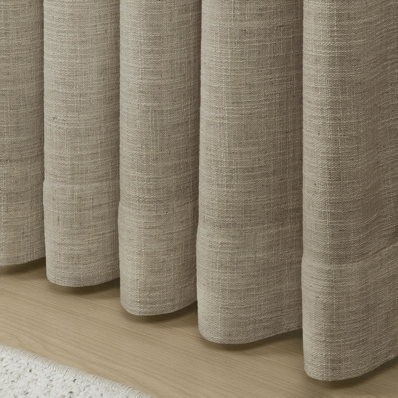 Grey Beige Liz Linen Pleated Curtains rounded curtain hems above a pale wood floor