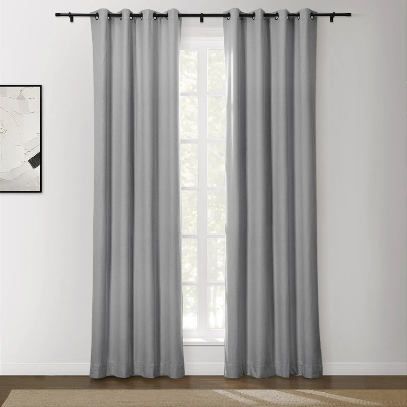 Photograph of textured grey grommet curtains on a black rod covering a window in a contemporary room, featuring an abstract black and white artwork and a beige herringbone rug