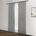Grey grommet top blackout curtains on a black rod frame a white window in a modern room featuring dark hardwood floors and an abstract black and white artwork