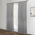 A contemporary room interior featuring long grey pleated curtains on a black rod, framing a multi-paned window, with dark wood flooring and a minimalist black and white abstract artwork on the adjacent white wall