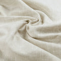 Light beige textured fabric draped in soft folds with subtle shadows highlighting its natural woven pattern