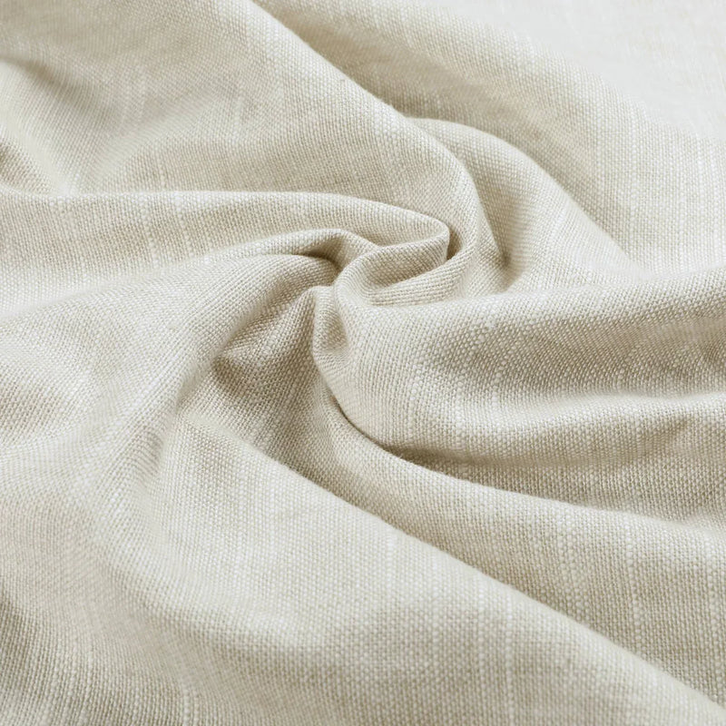 Light beige textured fabric draped in soft folds with subtle shadows highlighting its natural woven pattern