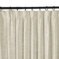 A light beige linen-look pleated curtain hanging from a black rod with rings showcasing its visible woven texture