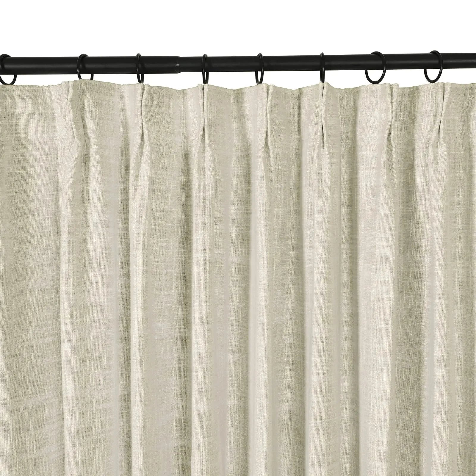 A light beige linen-look pleated curtain hanging from a black rod with rings showcasing its visible woven texture