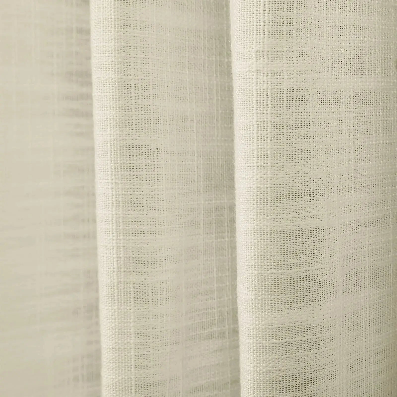 Photograph of a light beige sheer linen-look fabric curtain with prominent vertical folds and a detailed open-weave texture