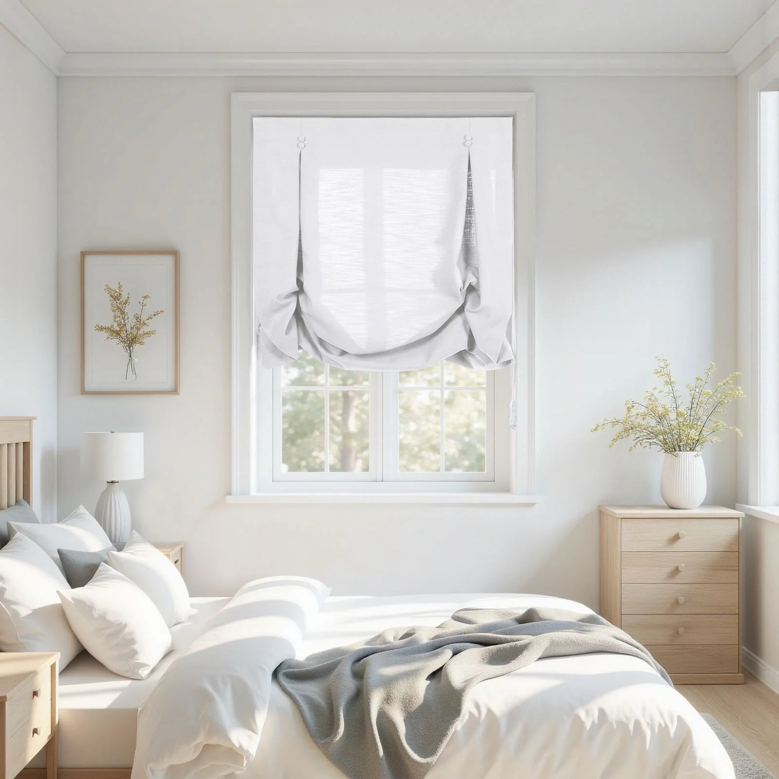 A bright modern minimalist bedroom featuring white hobbled Roman shades, light wood furniture, a bed with white linens and a grey throw, and dried yellow floral arrangements