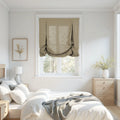 Photograph of a serene, modern bedroom interior featuring a natural linen tie-up Roman shade, light wood furniture including a bed with white bedding and a grey throw, and two arrangements of yellow wildflowers in a framed print and a ribbed white vase