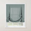 Duck egg blue textured tie-up balloon shade on a white window frame featuring decorative top loops and a softly gathered bottom with a blurred green landscape visible beyond