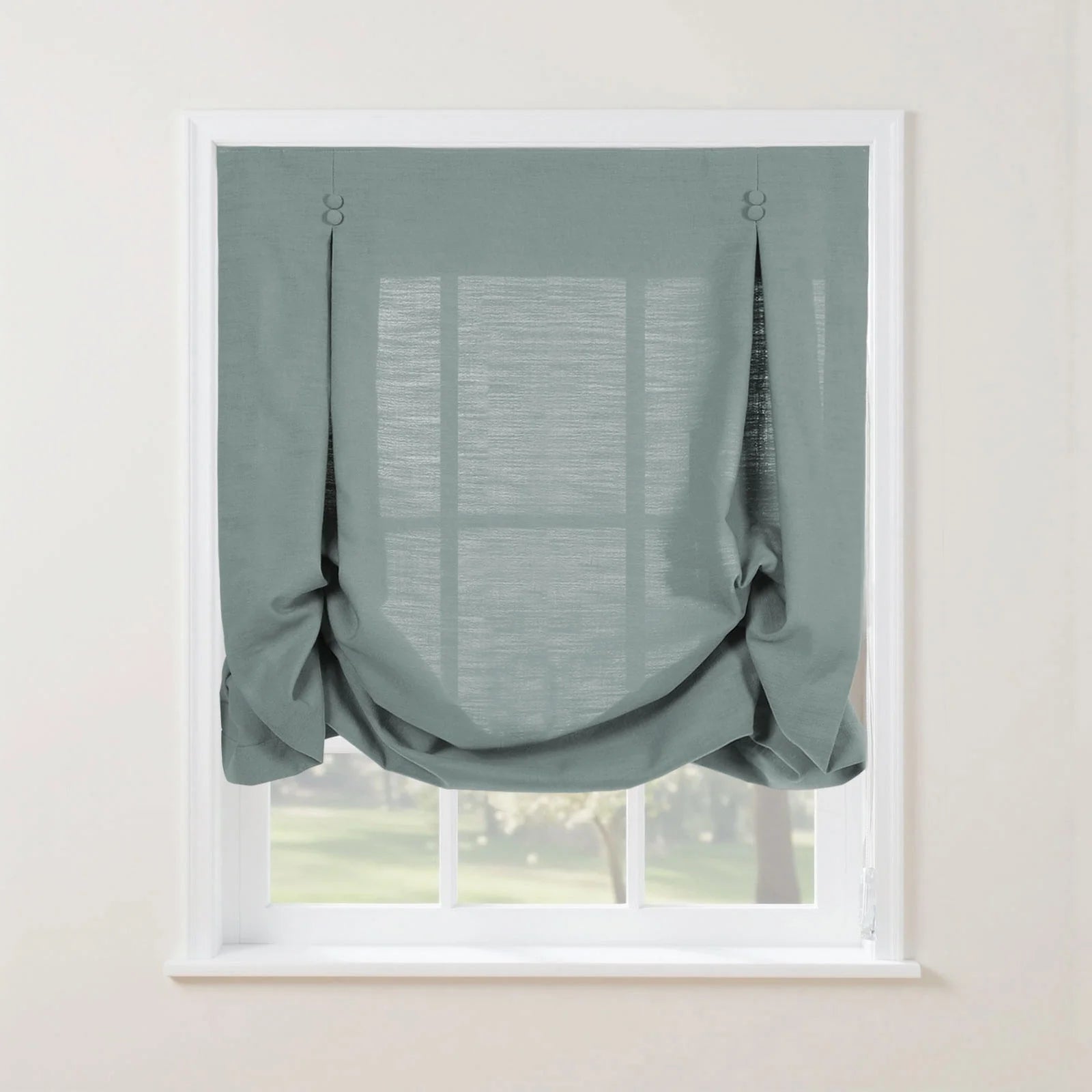 Duck egg blue textured tie-up balloon shade on a white window frame featuring decorative top loops and a softly gathered bottom with a blurred green landscape visible beyond