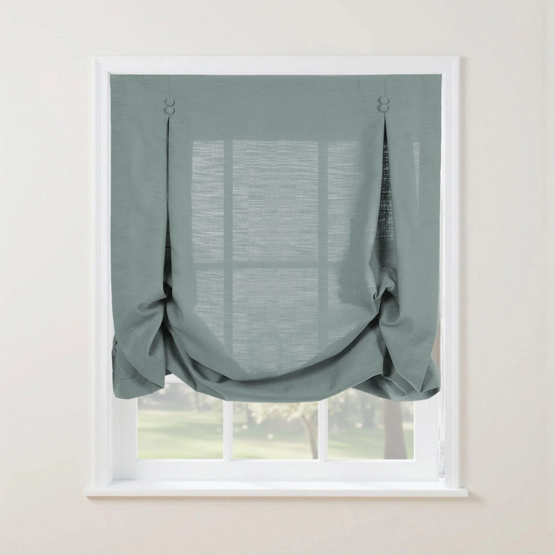 Duck egg blue textured tie-up balloon shade on a white window frame featuring decorative top loops and a softly gathered bottom with a blurred green landscape visible beyond
