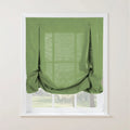 Product photo of a bright green textured faux linen Roman shade featuring top loops with two small round buttons and a softly gathered bottom edge, installed in a white window frame overlooking a vibrant outdoor garden